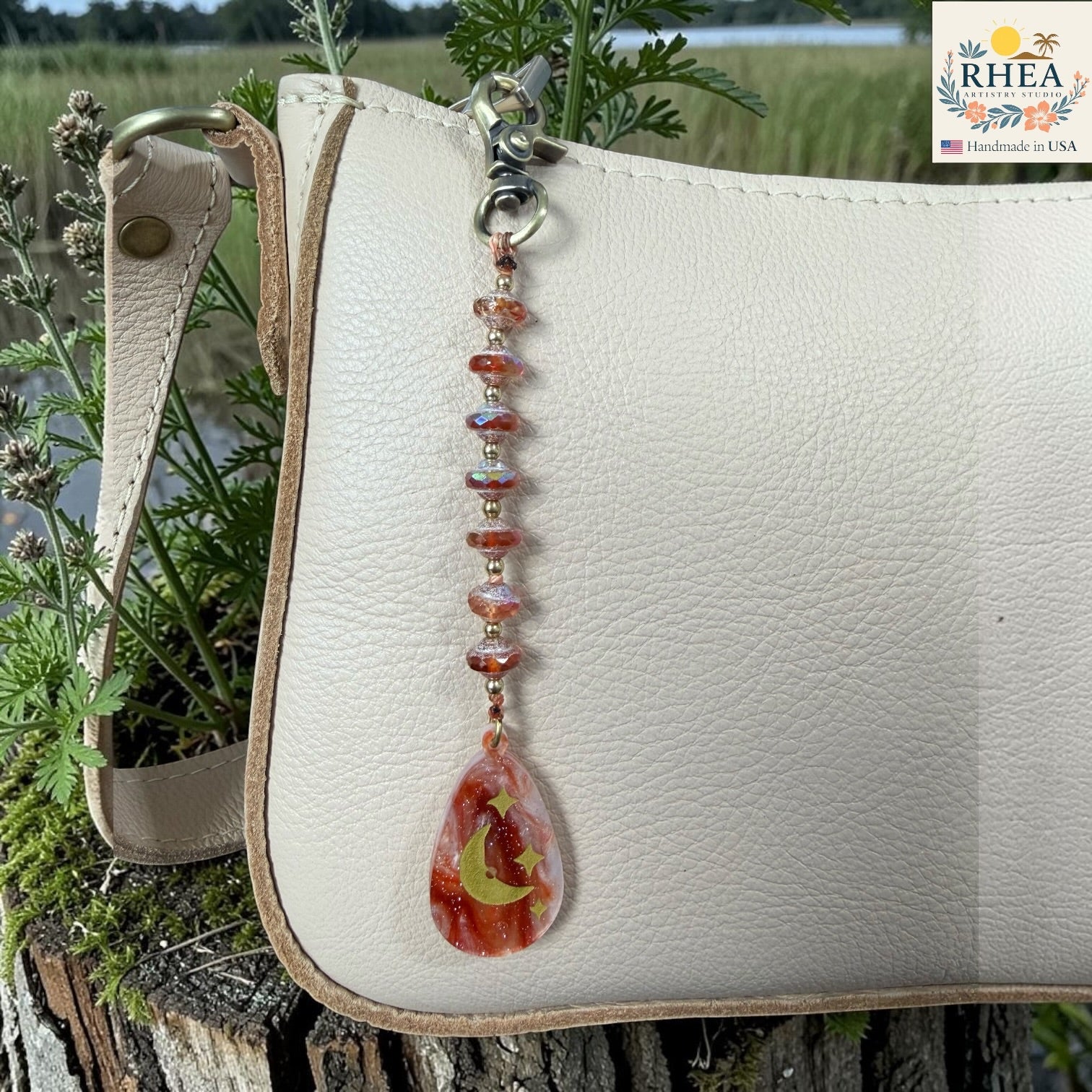 Beaded keychain with a teardrop design featuring a leaf and moon on a white leather bag with a natural background.