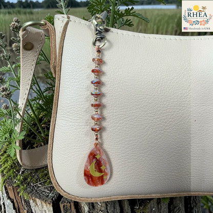 Beaded keychain with a teardrop design featuring a leaf and moon on a white leather bag with a natural background.