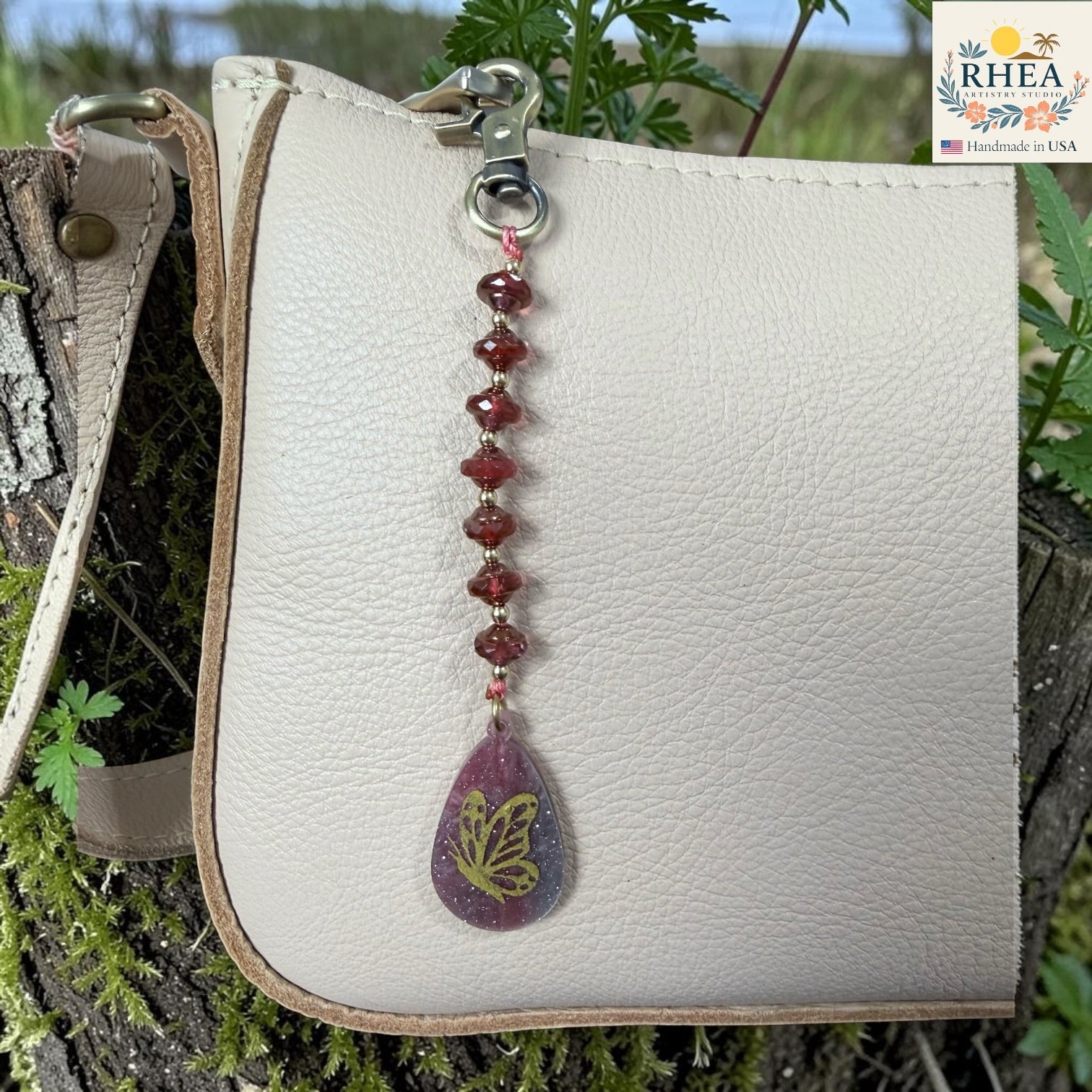 White leather pouch with a decorative keychain featuring a butterfly charm on a natural background.
