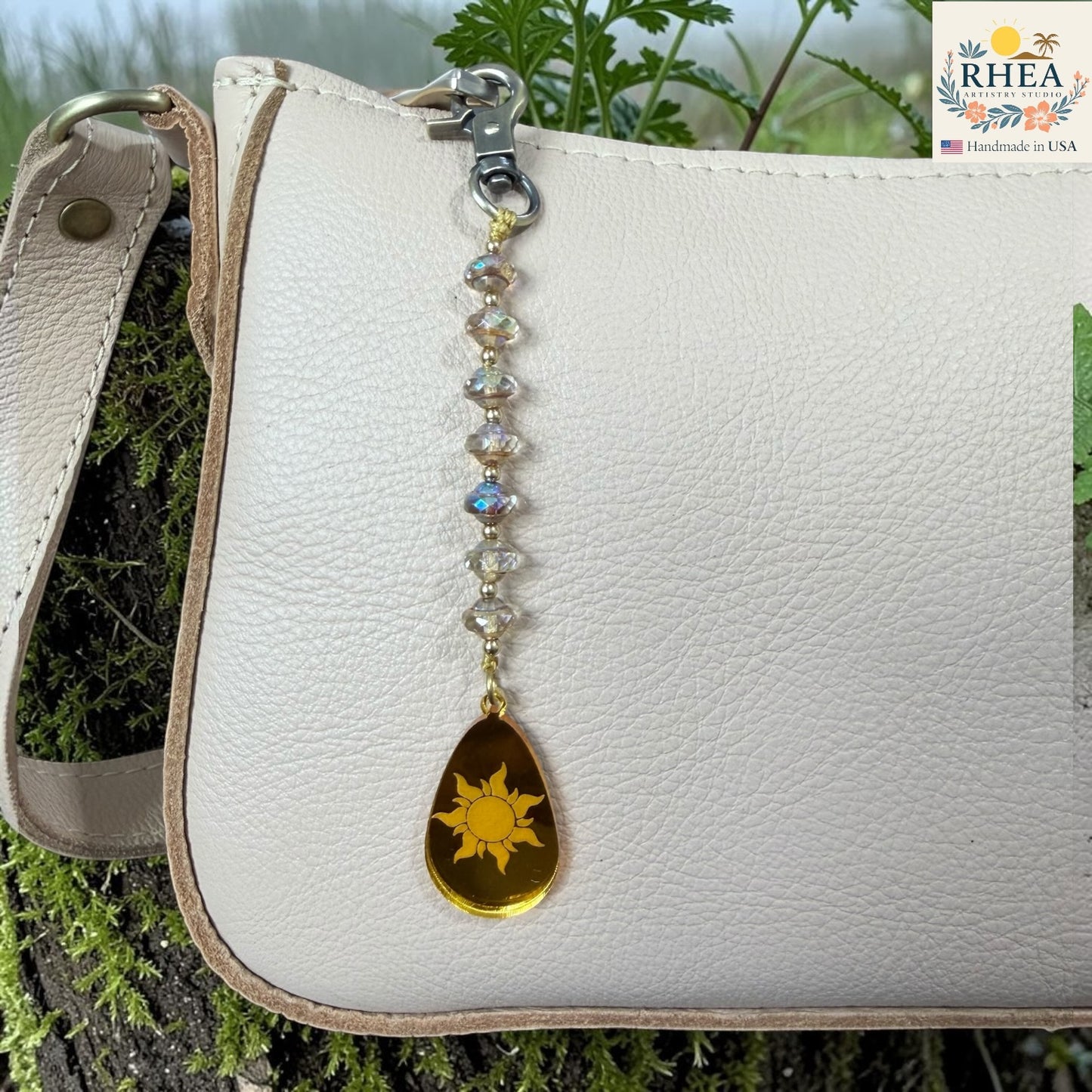 White leather bag with a sun-shaped keychain on a natural background