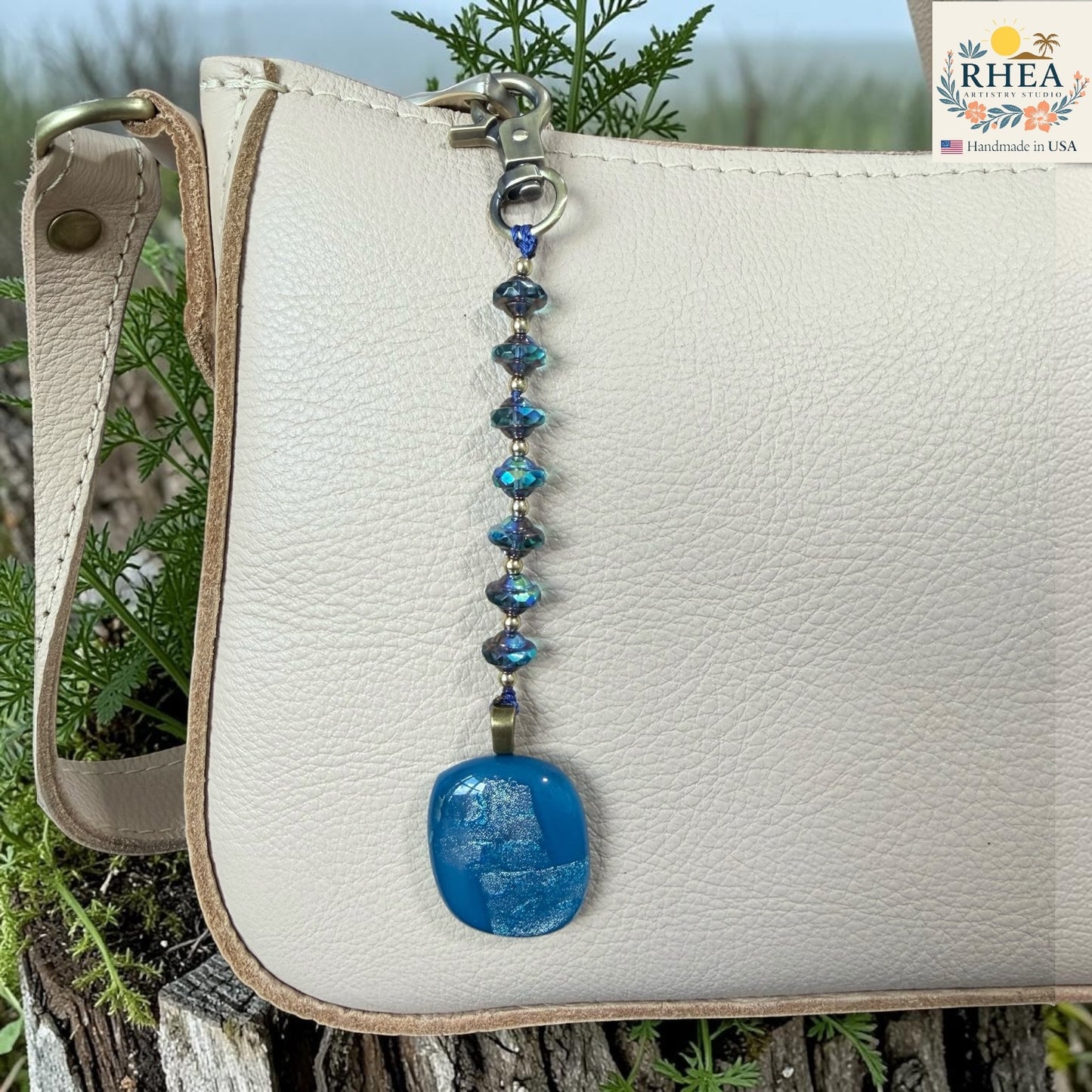 White leather bag with a blue beaded keychain on a natural background