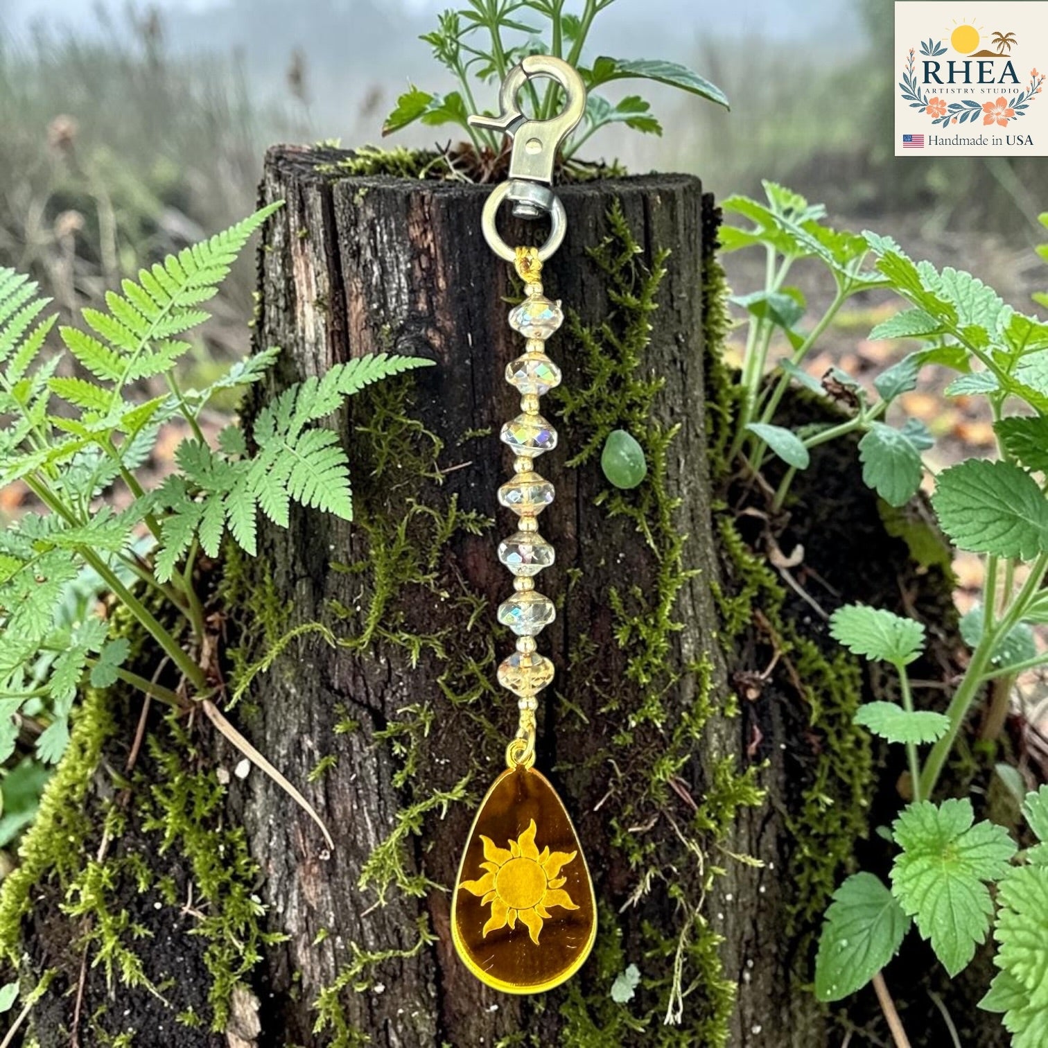 Keychain with sun design hanging on a tree stump with greenery