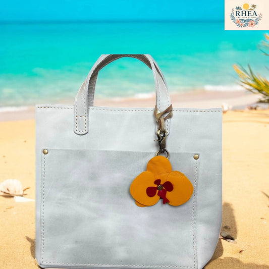 White tote bag with a floral keychain on a beach
