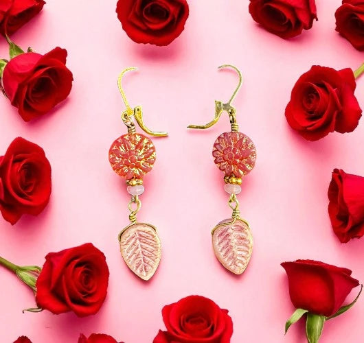 pink dahlia earrings with pink beads on a pink background with red roses