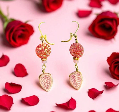 pink dahlia earrings on a pink background with red roses and petals