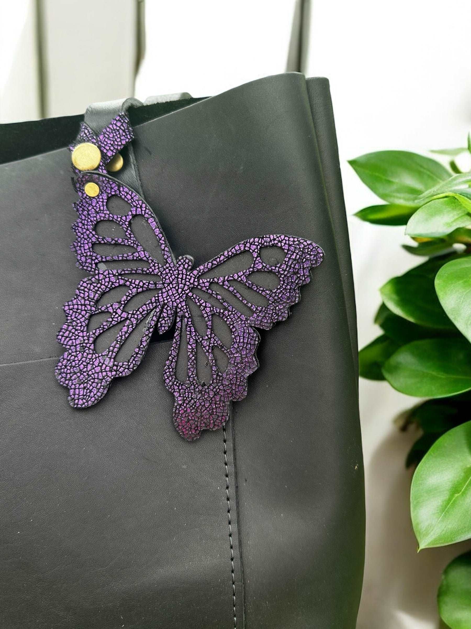 Elegant leather butterfly charm in a deep purple/grape color, crafted from halo metallic leather with a crackled finish, featuring a snap closure for attaching to purses or accessories.