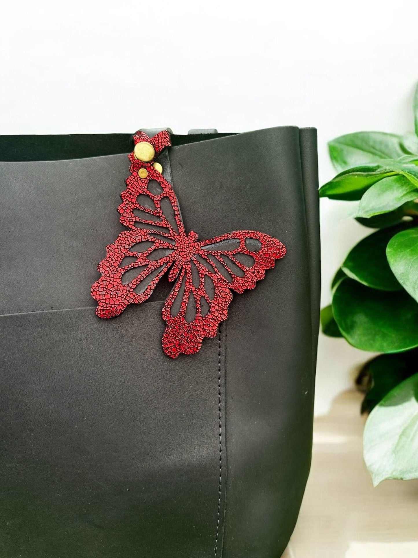 Handcrafted leather butterfly charm in a vibrant crackled red finish with halo metallic leather and a crackled texture, featuring a snap closure for easy attachment to accessories.