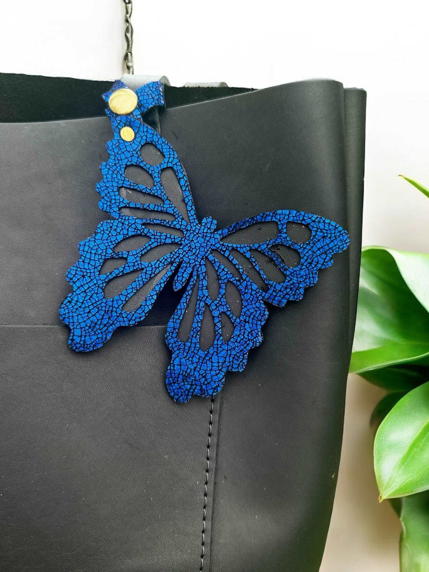 Handcrafted leather butterfly charm in a rich royal blue hue, made from halo metallic leather with a crackled look, designed with a snap closure for versatile use.