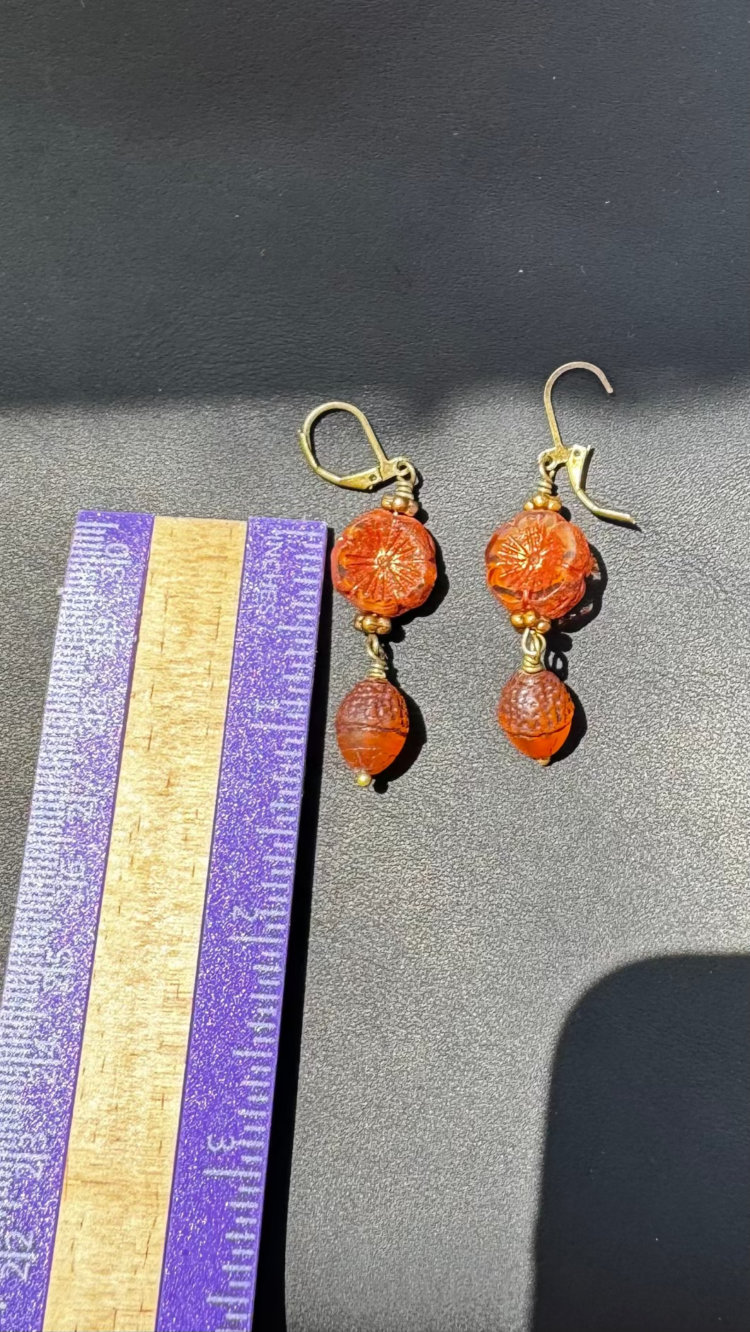 A pair of handcrafted Czech glass earrings with a serene glow, featuring a combination of rusty pink and brick orange hues, with brass hardware.