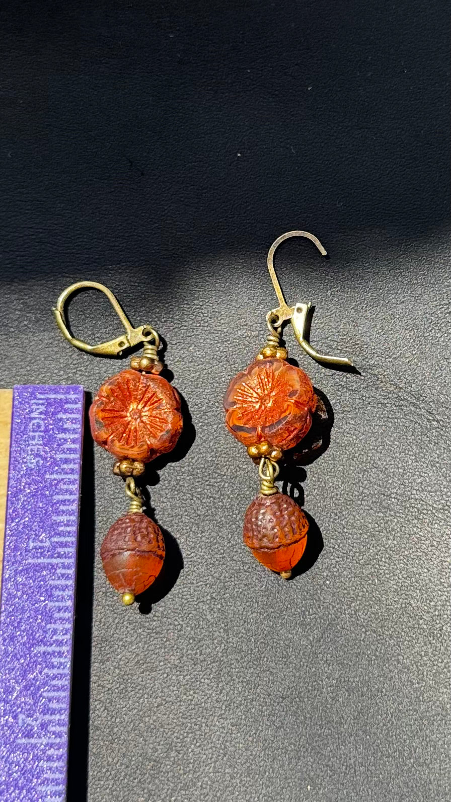 A pair of handcrafted Czech glass earrings with a serene glow, featuring a combination of rusty pink and brick orange hues, with brass hardware.
