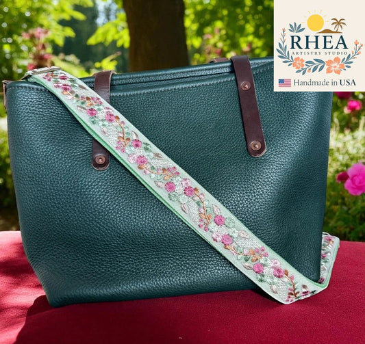 Teal handbag with floral strap on a red surface, with RHEEA Artistry Studios logo.