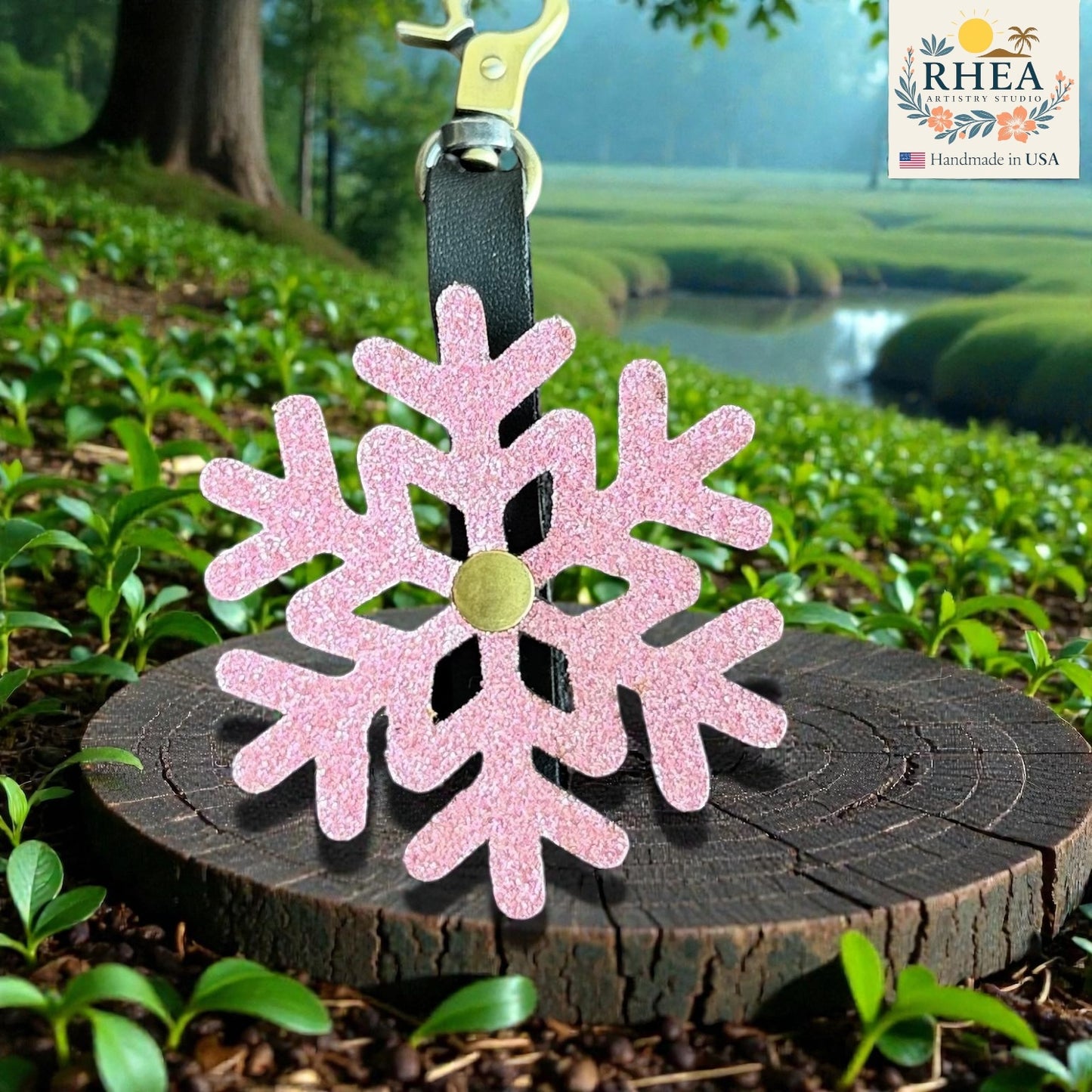 Pink glittery snowflake charm on a wooden stump with a scenic background