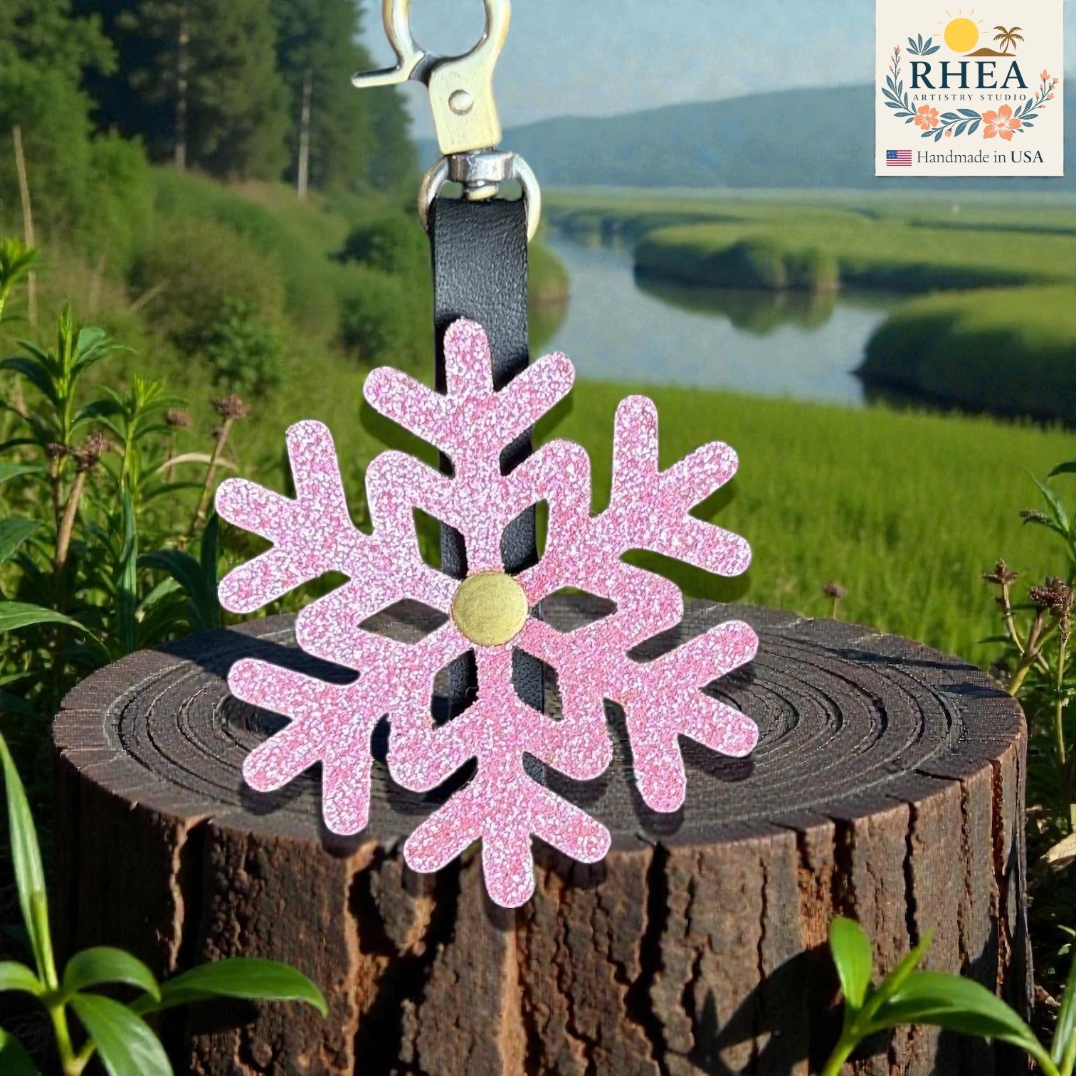 Pink glittery snowflake charm on a tree stump with a scenic background
