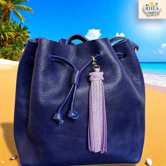 Blue leather bucket bag with a tassel on a beach background