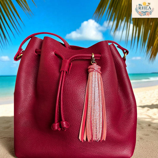 Red leather bucket bag with a tassel on a beach background