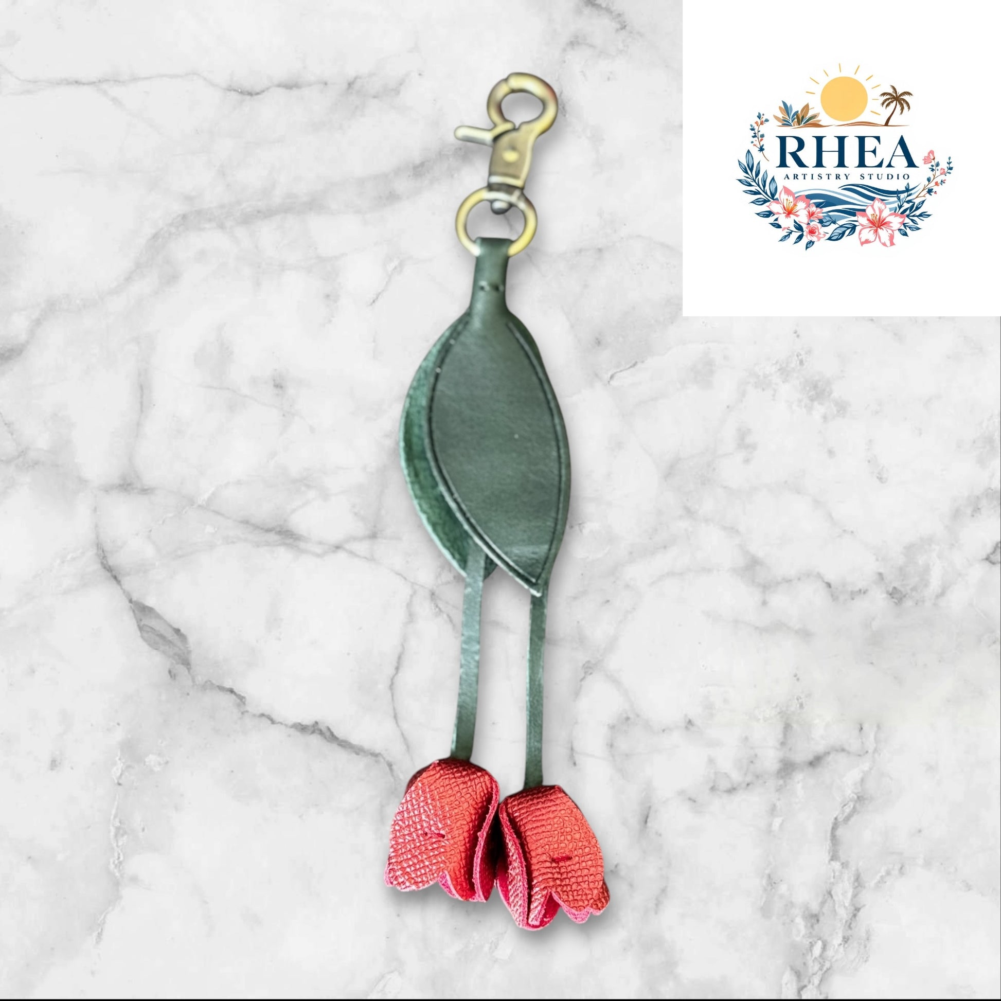 Green and red keychain on a white surface with grass and flowers in the background