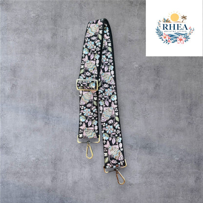 Adjustable embroidered purse strap with floral patterns and gold hardware, displayed on a gray background.