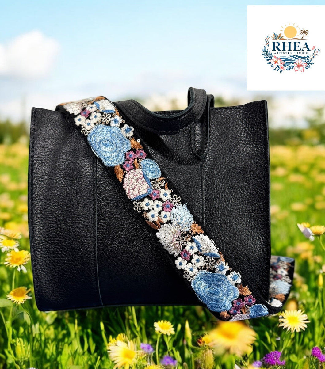 Black leather bag with richly embroidered wide strap featuring sky blue and ivory jumbo roses by Rhea Artistry Studio.