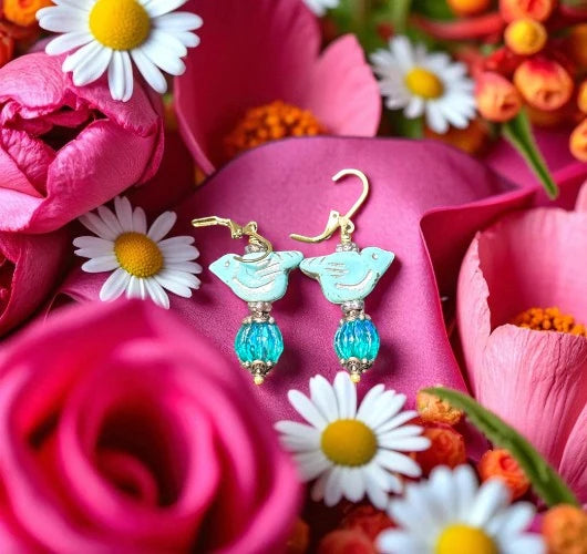 Earrings with blue beads on a bed of pink flowers and daisies