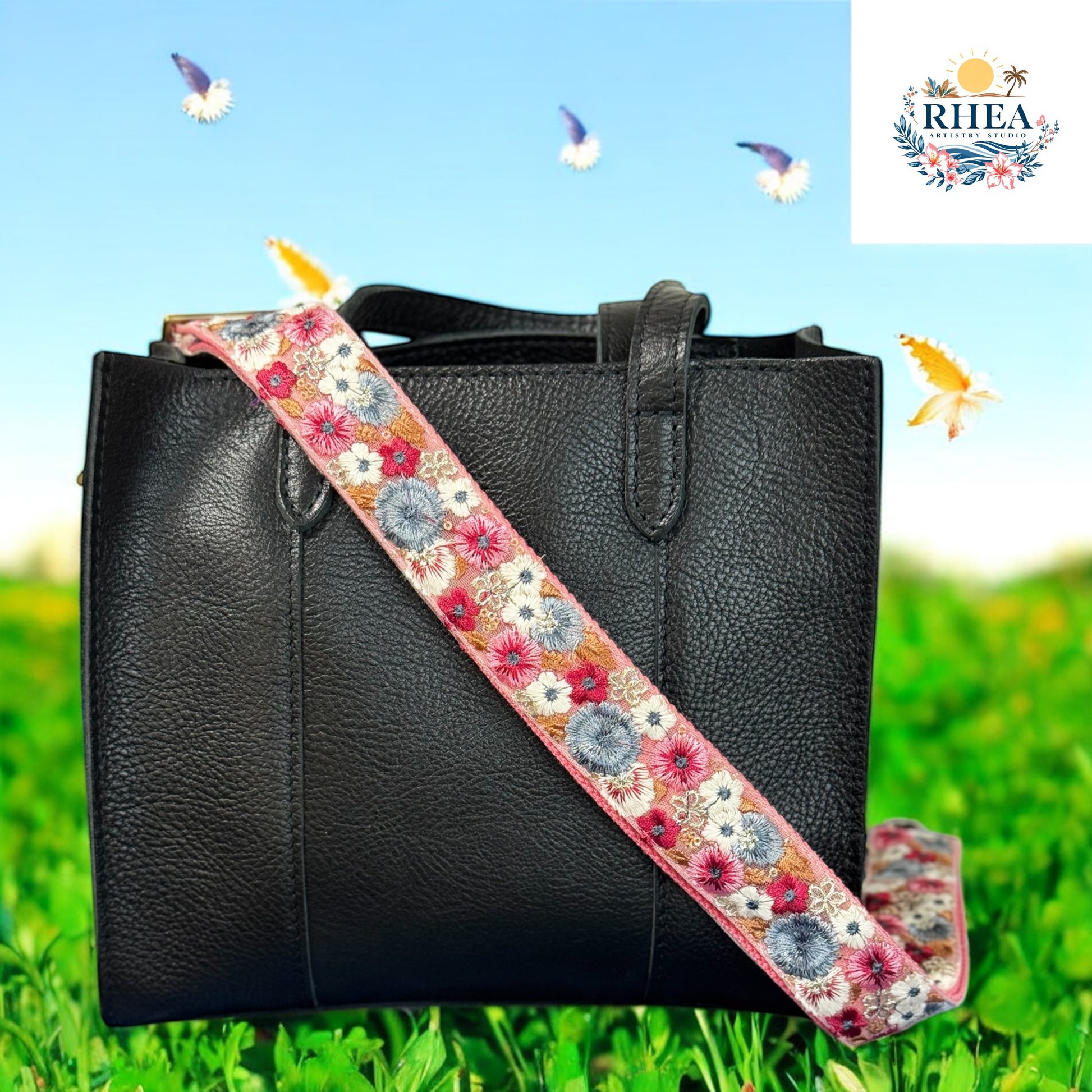 A handcrafted embroidered strap featuring intricate floral patterns in coral, blue, and white rests on a black leather bag at the garden