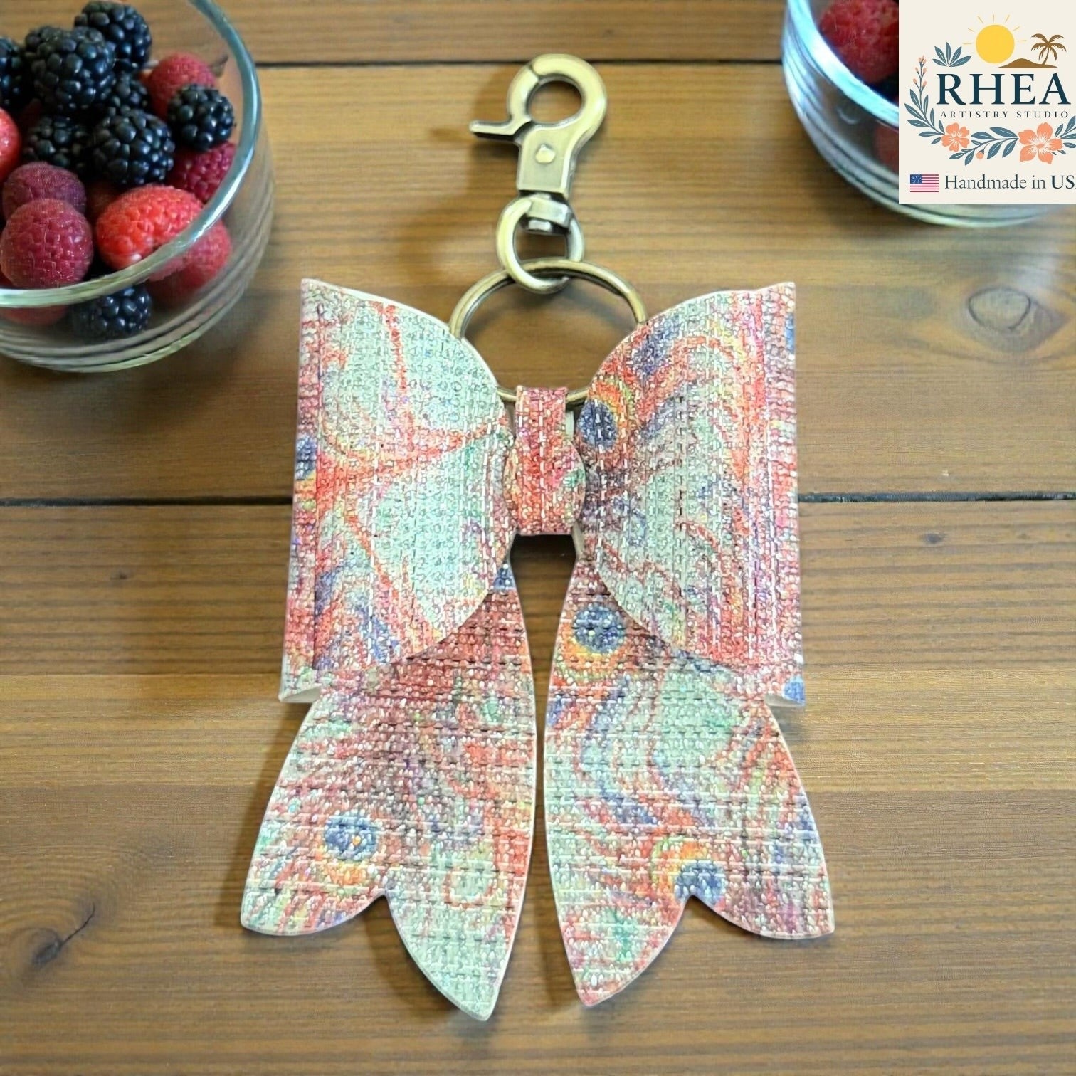 Butterfly-shaped purse charm with colorful pattern on a wooden surface, next to a container of berries.