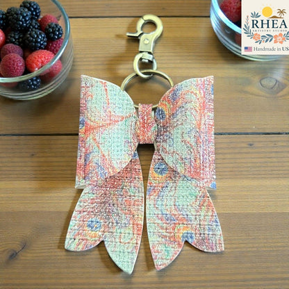 Butterfly-shaped purse charm with colorful pattern on a wooden surface, next to a container of berries.
