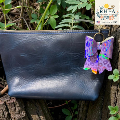 Blue leather pouch with a colorful butterfly purse charm on a natural background