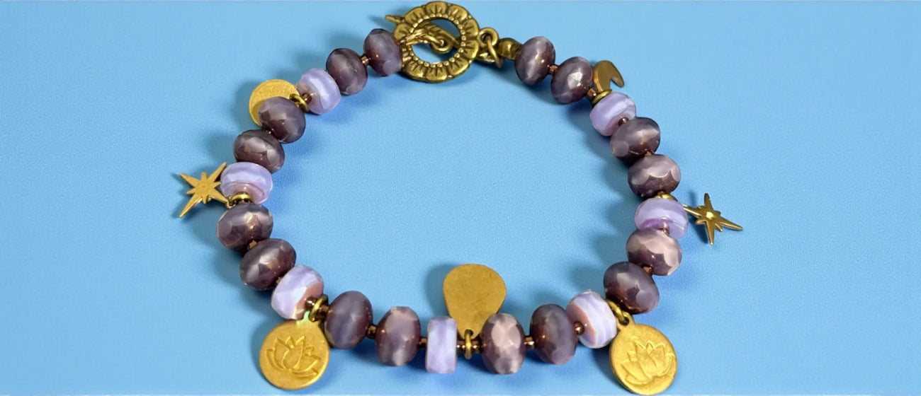 Bracelet with brown and pink beads and gold charms on a blue background