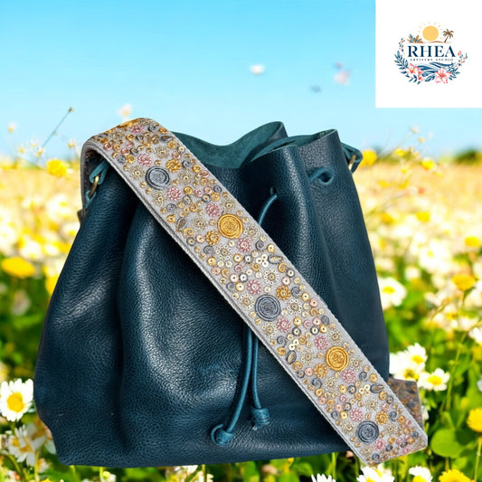 Sun & Moon Medley embroidered strap with teal leather bucket bag against garden background