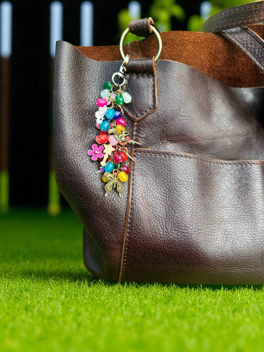 Brown leather handbag with a colorful keychain on grass