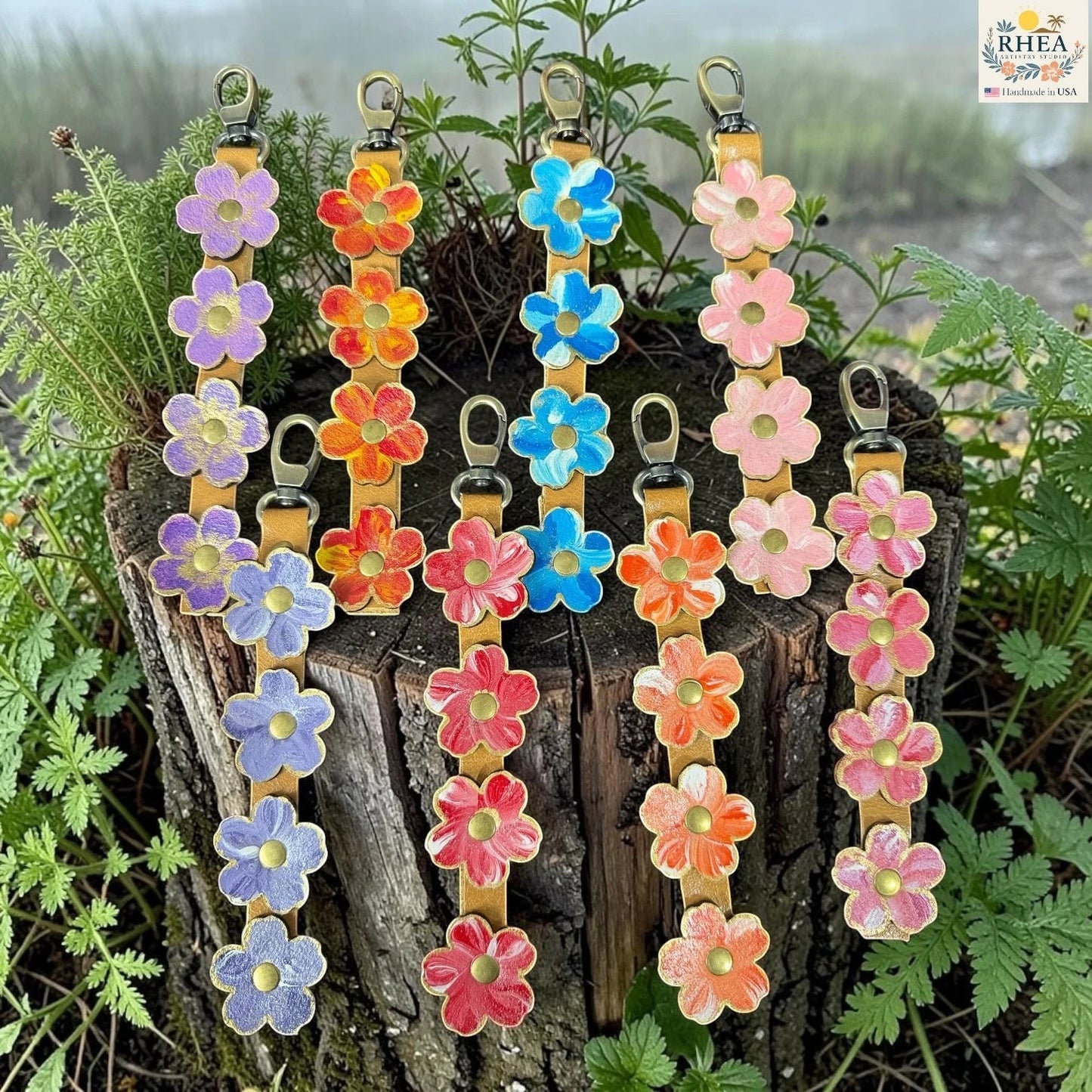 Colorful flower-shaped keychains on a wooden block with green plants in the background