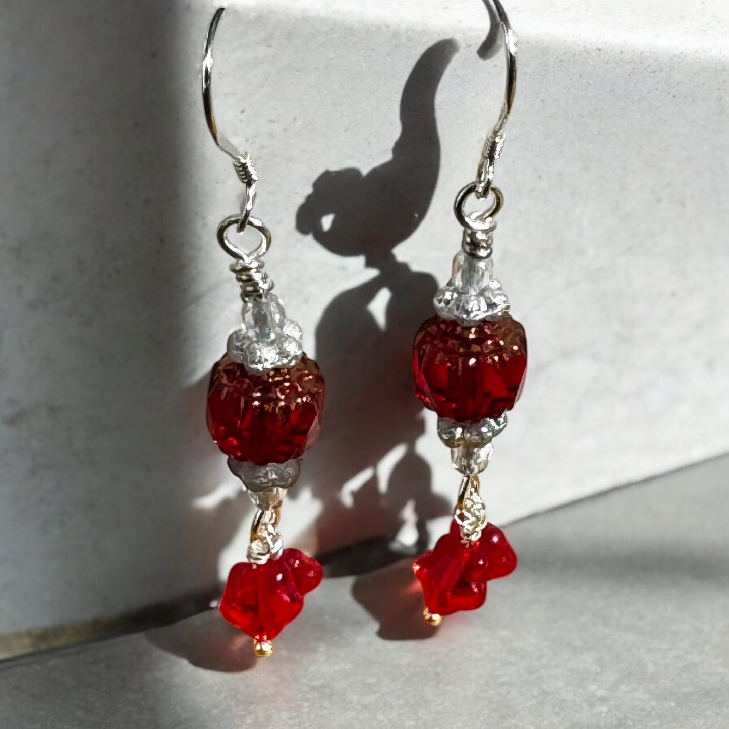 Red beaded earrings with silver hooks on a light gray background