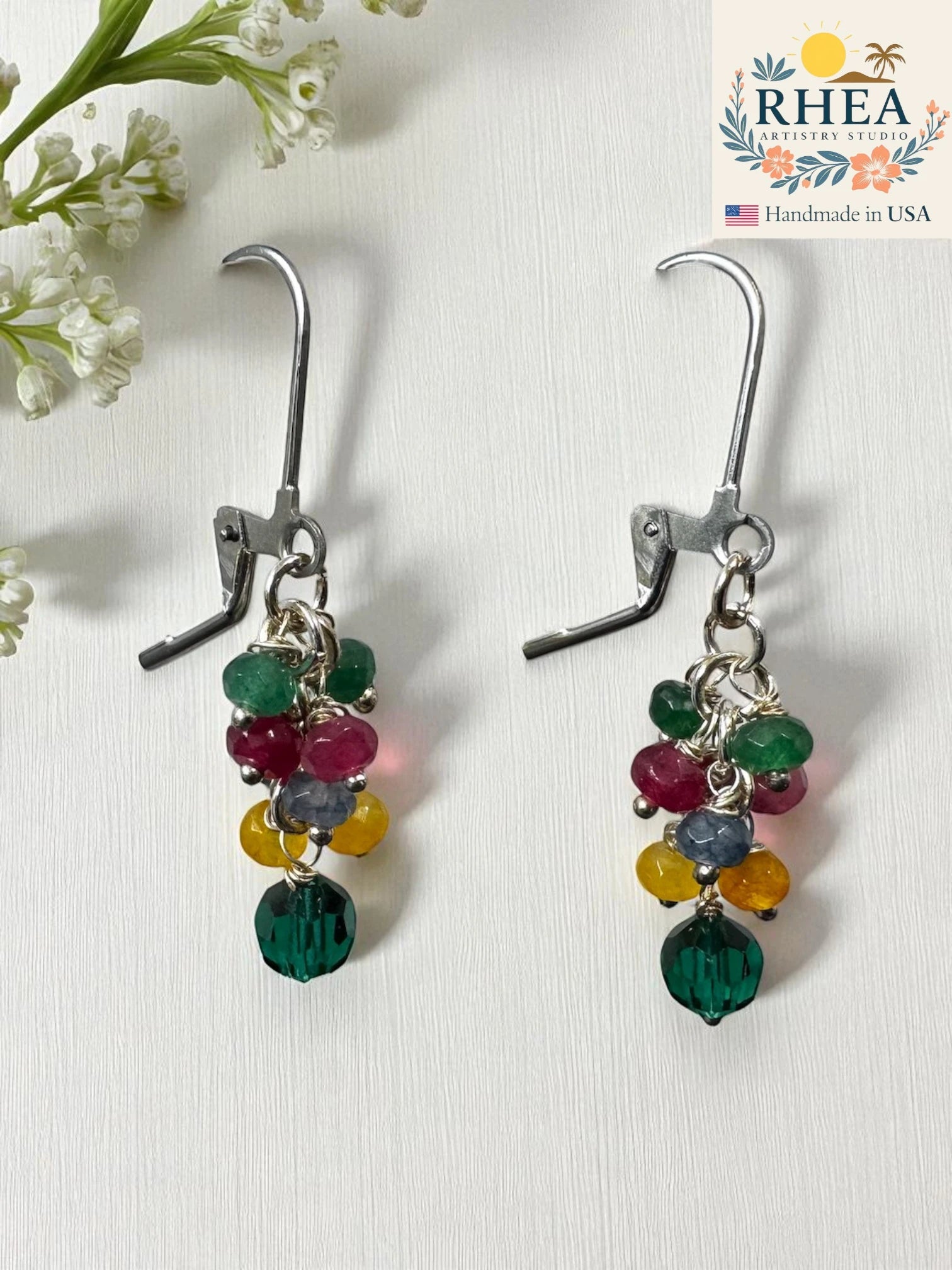 Multicolored beaded girls earrings on a white background with 'RHEA' branding.