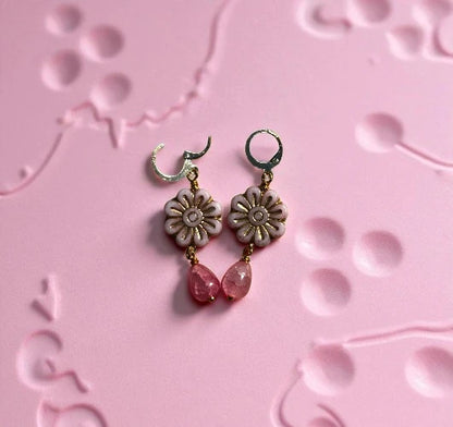 Floral earrings with pink beads on a pink textured background