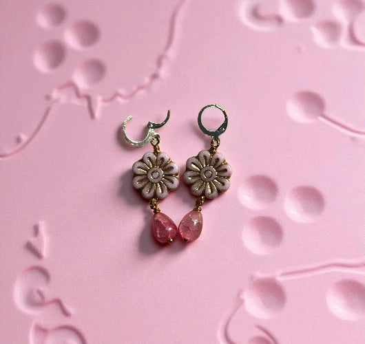 Floral earrings with pink beads on a pink textured background