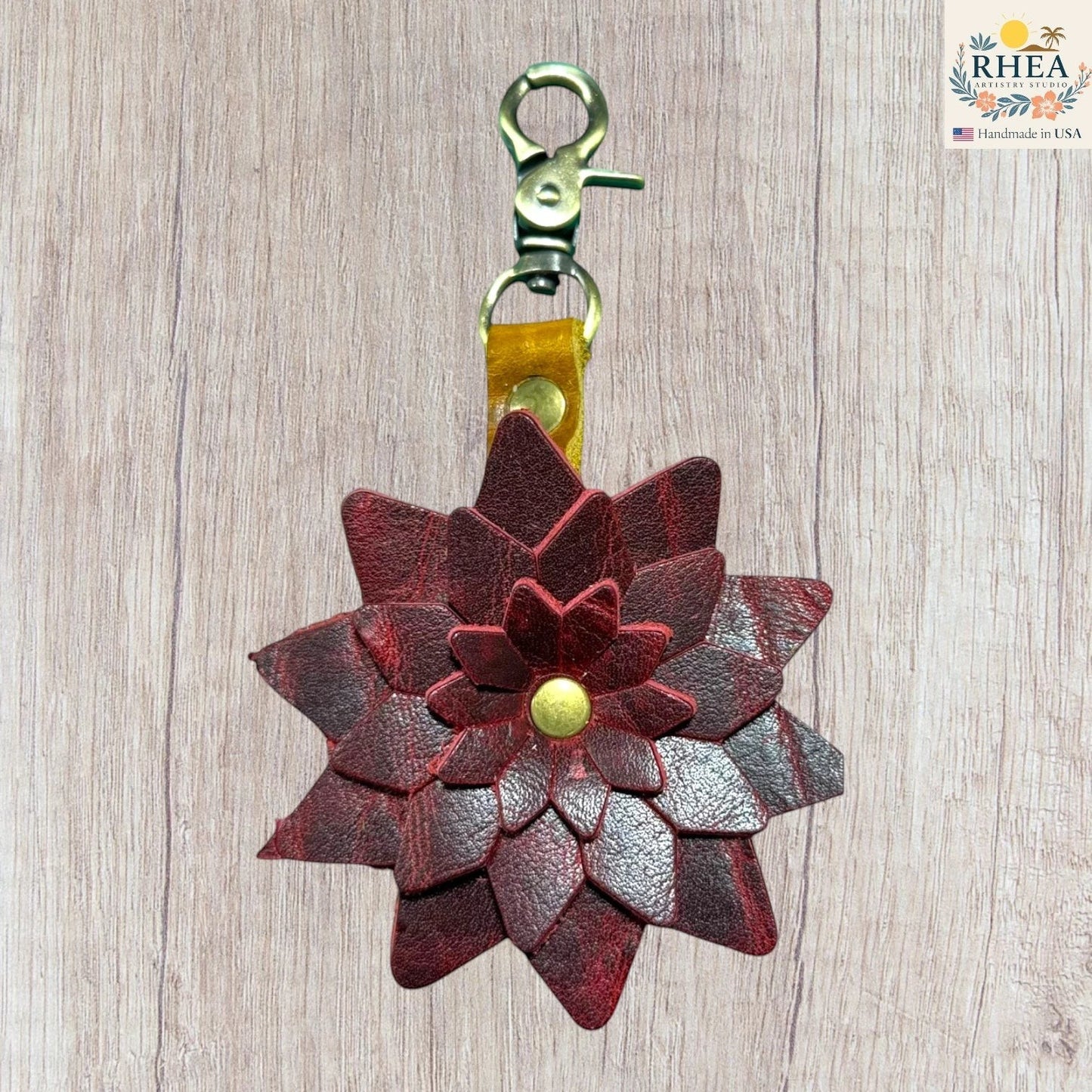 Leather flower keychain with a gold clasp on a wooden surface, Handmade leather bag charm featuring layered petal construction