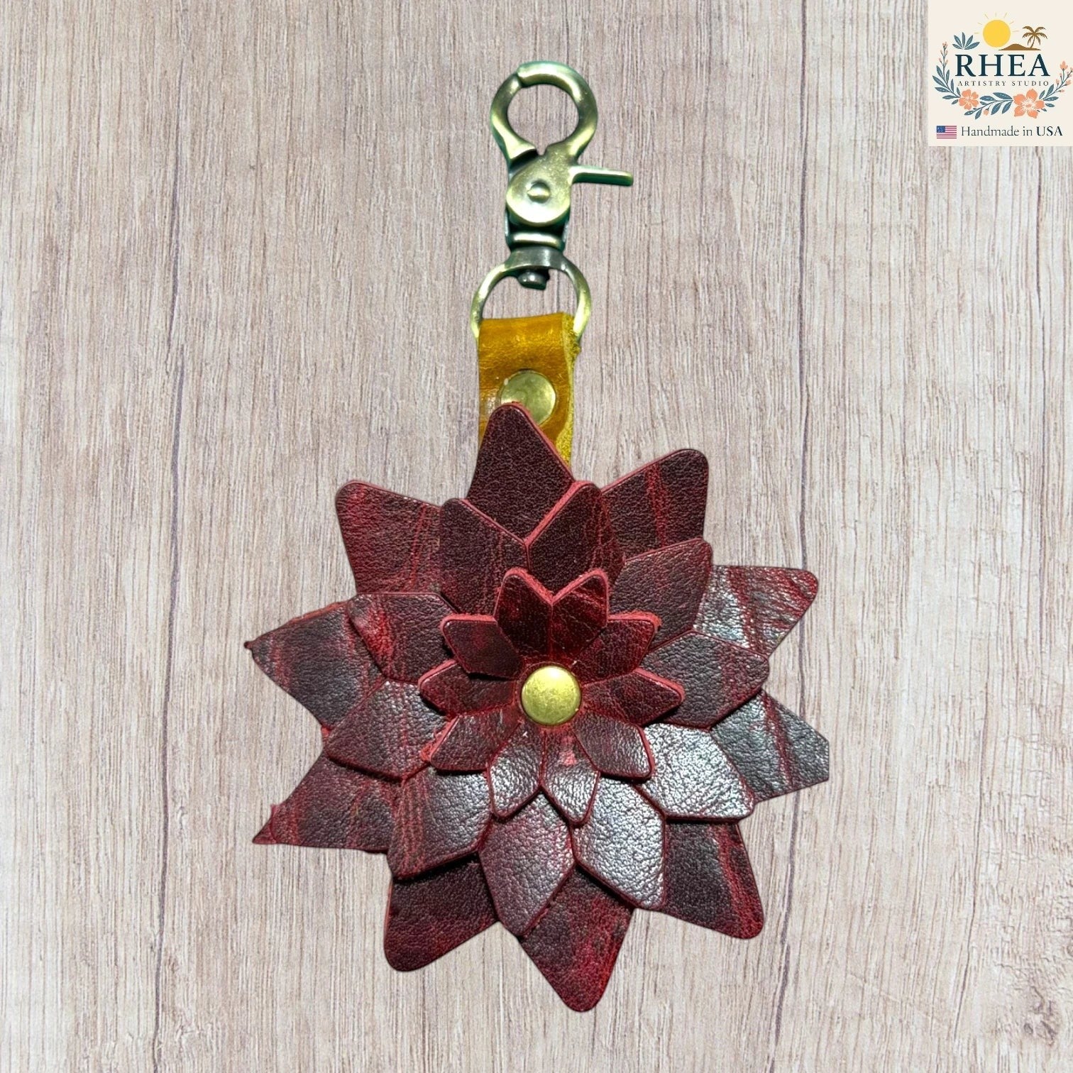 Leather flower keychain with a gold clasp on a wooden surface, Handmade leather bag charm featuring layered petal construction