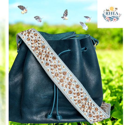 Canyon Blossom embroidered strap with navy leather bucket bag against garden background