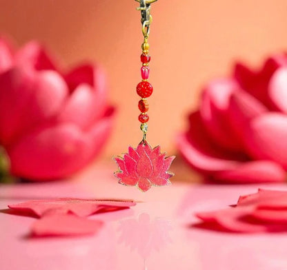 Decorative pink lotus charm with beads against a pink background with lotus flowers.
