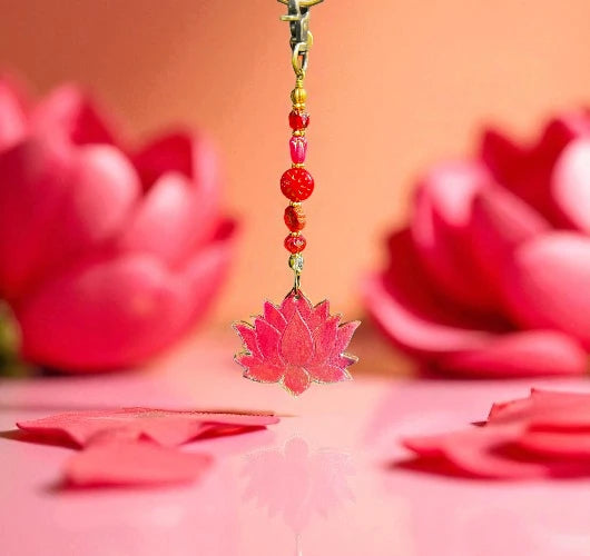 Decorative pink lotus charm with beads against a pink background with lotus flowers.