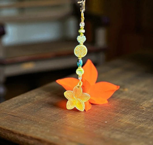 Decorative keychain with beads and a flower charm on a wooden surface