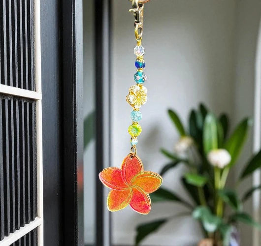 Decorative keychain with colorful beads and a red flower charm hanging on a door.