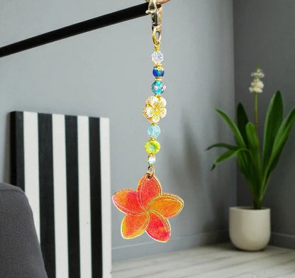 Decorative keychain with colorful beads and a floral design hanging against a neutral background.
