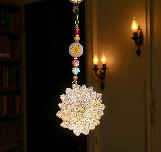 Decorative keychain with floral design and colorful beads hanging against a dark background.