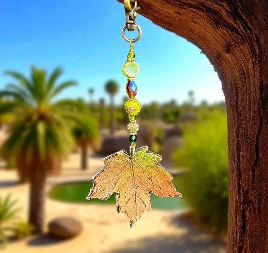 Decorative leaf charm with beads hanging from a tree in a desert setting