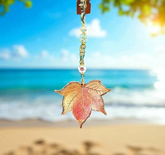 Decorative leaf charm with beads against a beach background