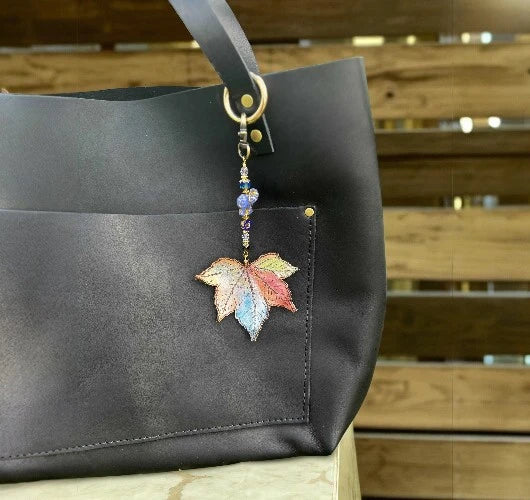 Black handbag with a colorful leaf charm on a wooden surface