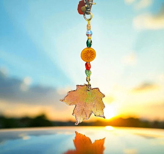 Decorative leaf charm with beads against a sunset sky