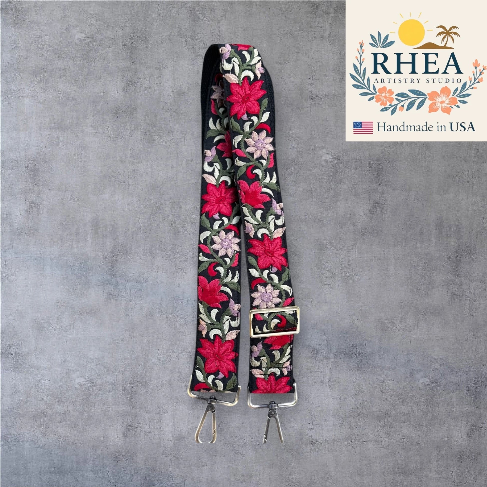 Floral patterned purse strap with RHEA Artistry Studio logo on a gray background