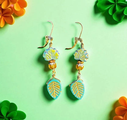 Pair of earrings with leaf designs on a green background